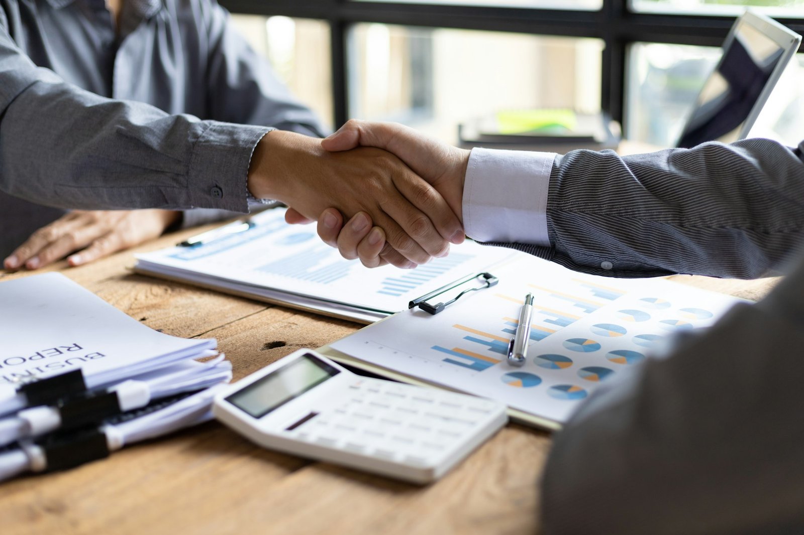 Handshake. Businessman on desk shaking hands with accountant or financial advisor in office.